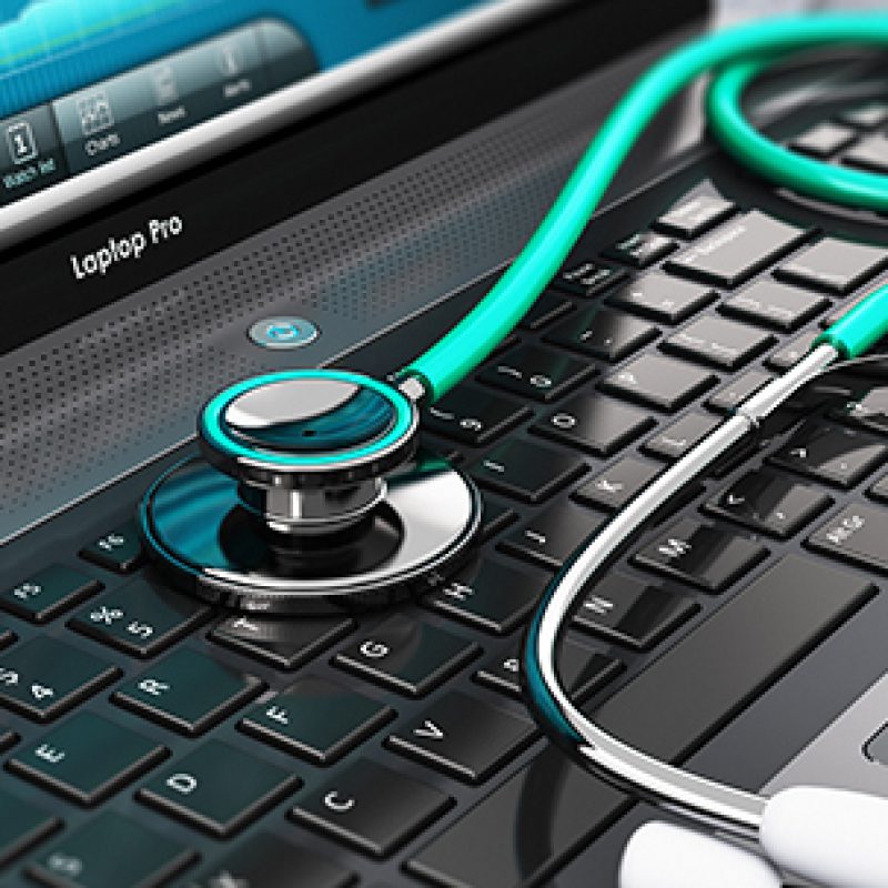 Creative abstract healthcare, medicine and cardiology tool concept: laptop or notebook computer PC with medical cardiologic diagnostic test software on screen and stethoscope on black wooden business office table with selective focus effect